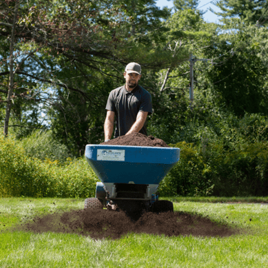 Lawn care technician applying nutrient-rich compost topdressing to improve soil health and support lawn recovery.