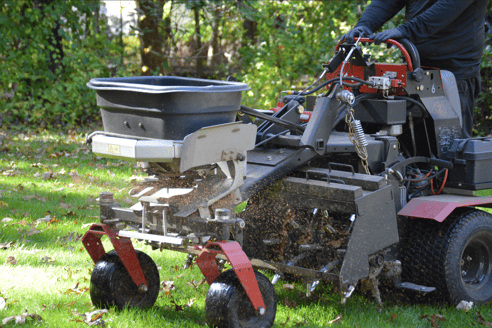 Professionally applying grass seed during overseeding process for lawn rejuvenation