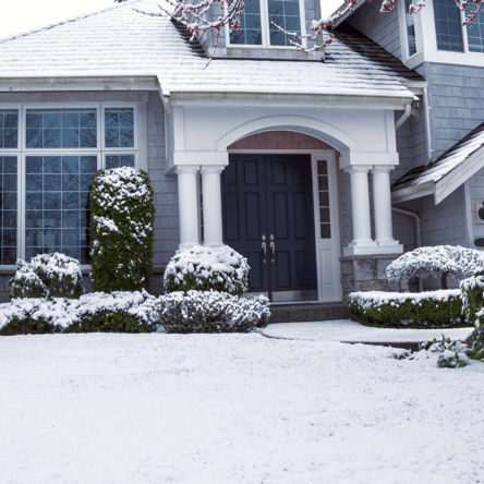 Shoveling snow from a driveway with a plastic shovel to avoid damaging the lawn during winter snow removal